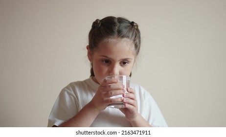 Child Drinking Water. Little Girl In The Kitchen Drinks Water From A Glass Cup. Problem Of Shortage Of Drinking Water In The World Concept. Kid Drinking Clean Water From Lifestyle A Glass