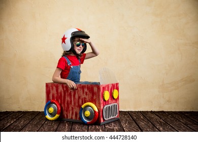 Child Driving A Car Made Of Cardboard Box. Kid Having Fun At Home. Travel And Summer Vacation Concept