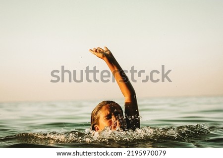 Child drowning in water holding hand above a surface of green water, going deep. Accident in a river, sea, ocean. Dangerous situation on summer coast. Help me concept. Teenage girl drowns. Film filter