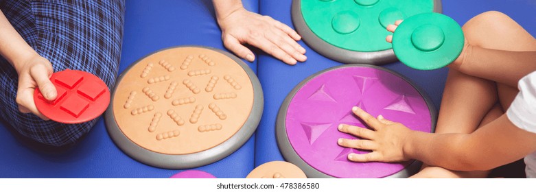 Child During Sensory Integration Therapy Touching A Colorful Tactile Disc, Panorama