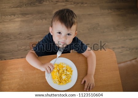 the child eagerly in the kitchen eating scrambled eggs, day, the view from the top