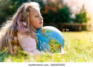 Child with Earth Globe. Portrait of a blonde European girl of elementary school with an educational globe of the planet Earth in nature in sunny weather. Study, education, conservation and - Powered by Shutterstock