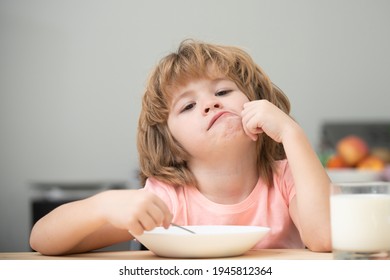 Child eat. Unhappy Caucasian child sit at table at home kitchen have no appetite. Upset little kid refuse to eat organic cereals with milk. Little healthy hungry boy eating soup from with spoon