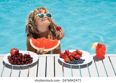 Child eat watermelon. Kid with summer fruits in pool. Portrait of summer kids. Child in swimming pool playing and relaxed in water. Summer vacation with kids.