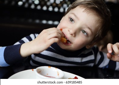 Child Eating Chicken Nugget In A Restaurant