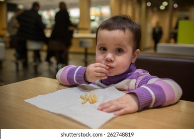 Child Eating French Fries In Fast Food