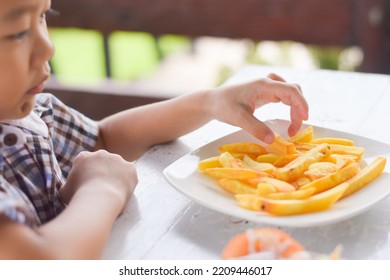 Child Eating French Fries Or Potato Chips.