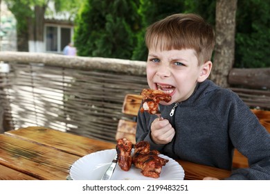 Child Eating Grilled Chicken Wings On Restaurant Terrace