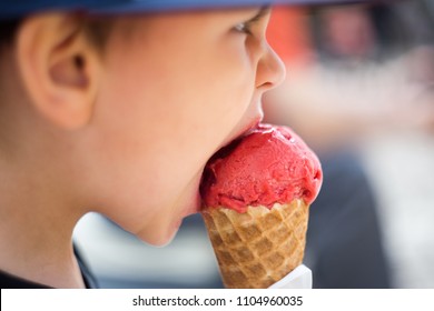 The Child Is Eating Ice Cream. Little Boy Takes A Bite Out Delicious Ice Cream