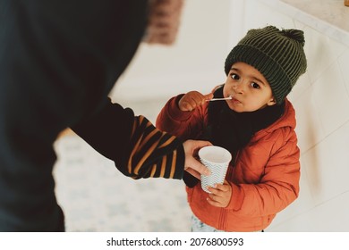 Child Eating Milkshake Indoor Helped By His Mum