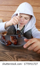 Child Eating Pork Ribs On Wooden Terrace