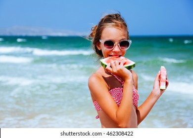 Child eating watermelon on the beach in summer sunny day