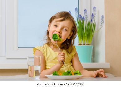 The child eats broccoli with an appetite. Organic Cabbage and food on a plate. Green healthy vegetables rich in vitamins. Proper nutrition concept.