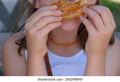 The Child Eats A Bun With A Big Appetite. Shallow Depth Of Field.