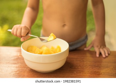 A child eats fresh fruit pineapple on a hot Sunny day. Healthy diet. Close - up of hands and a plate of fruit. summer time. vacation