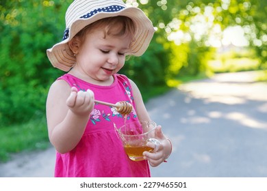 A child eats honey in the park. Selective focus. Kid. - Shutterstock ID 2279465501
