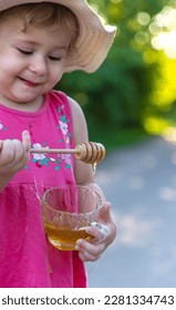 A child eats honey in the park. Selective focus. Kid. - Shutterstock ID 2281334743