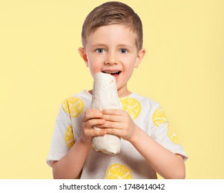 A Child Eats A Shrimp Roll. The Boy Is Holding A Roll In Pita Bread, About To Take A Bite Out Of It. Beautiful European Boy Eating Fast Food. Happy Child. Favorite Children's Food.