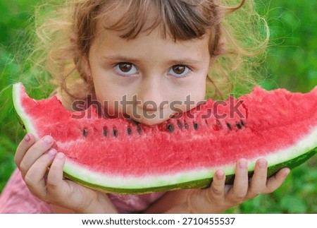 A child eats an watermelon in the park. Selective focus. Kid.