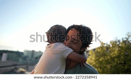 Child embracing father in sunset time. Father and son bonding moment during Golden Hour Time. Parent and small boy hug. Fatherhood concept