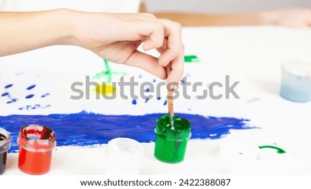 The child is engaged in drawing. ?reative development of the kid through painting with paints. Colored children's education background.