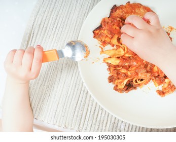 A Child Enjoying A Plate Of Lasagna At Dinner