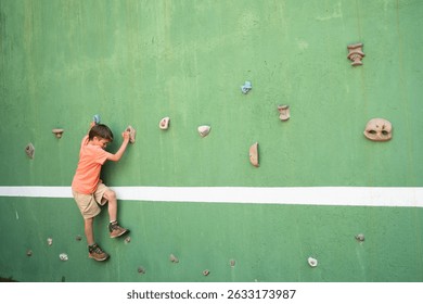 Child enjoys bouldering on a climbing wall, having fun while exercising