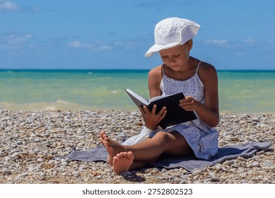 Child exploring a book while sitting on the seaside stones