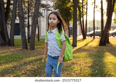 Child exploring park with green backpack during golden hour - Powered by Shutterstock