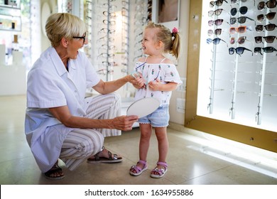 Child At Eye Sight Test. Little Kid Selecting Glasses At Optician Store