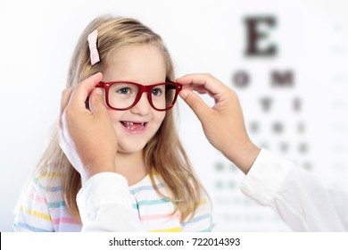 Child At Eye Sight Test. Little Kid Selecting Glasses At Optician Store. Eyesight Measurement For School Kids. Eye Wear For Children. Doctor Performing Eye Check. Girl With Spectacles At Letter Chart.