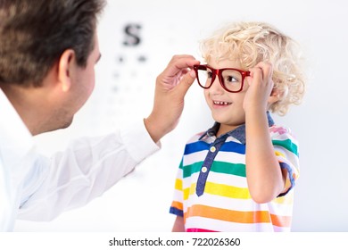 Child At Eye Sight Test. Little Kid Selecting Glasses At Optician Store. Eyesight Measurement For School Kids. Eye Wear For Children. Doctor Performing Eye Check. Boy With Spectacles At Letter Chart.