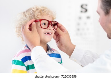 Child At Eye Sight Test. Little Kid Selecting Glasses At Optician Store. Eyesight Measurement For School Kids. Eye Wear For Children. Doctor Performing Eye Check. Boy With Spectacles At Letter Chart.