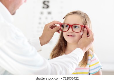 Child At Eye Sight Test. Little Kid Selecting Glasses At Optician Store. Eyesight Measurement For School Kids. Eye Wear For Children. Doctor Performing Eye Check. Girl With Spectacles At Letter Chart.