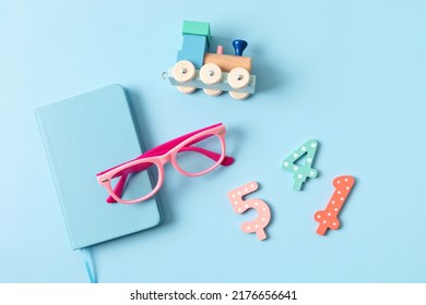 Child Eyeglasses Over Blue Pastel Background. Optical Store, Glasses Selection For Kids, Eye Test, Vision Examination At Optician Concept. Top View, Flat Lay