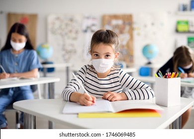 Child With Face Mask Back At School After Covid-19 Quarantine And Lockdown, Writing.