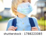 Child in face mask going at reopen school after covid-19 quarantine and lockdown. It is new normal for protection and prevention while outbreak of coronavirus or flu. Kids back to school concept.