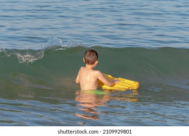 Child Facing The Sea Waves With A Floating Tablet