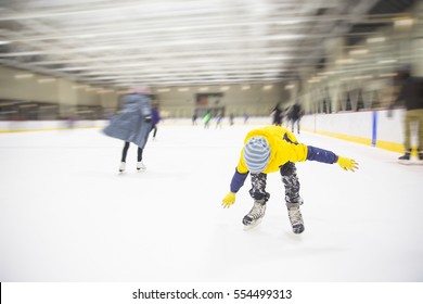 Child Falling Down On The Ice Rink. The Boy Lost His Balance On Skates. Blurred Background Due To The Concept. Empty Space For Your Text