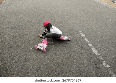 Child Falling While Roller Skating on Asphalt Road – Kid Wearing Protective Gear and Pink Helmet