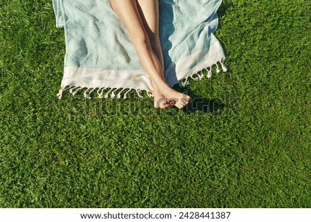  Child feet on green grass, barefoot little girl on meadow. Sunbathing on the green grass - lifestyle, concept of grounding and connecting with nature.