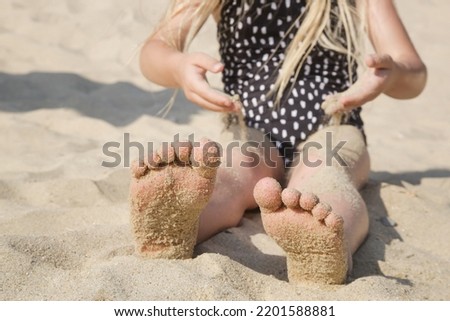 Child feet in the sand on a beach. Summer vacation on seaside.