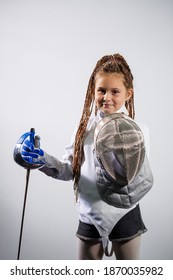 A child in a fencing costume is holding an epee. Girl learning fencing