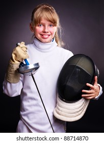 Child in fencing costume holding epee . Black background.