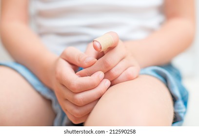 Child finger with an adhesive bandage.