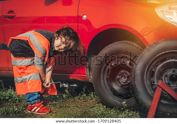 Child\
fixing the car changing the wheel alone\
outdoor