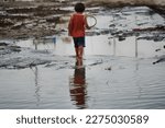 Child flood victim walks alone on the street. High quality photo