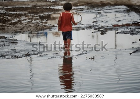 Child flood victim walks alone on the street. High quality photo