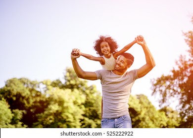 Child flying on father shoulders while held piggyback - Powered by Shutterstock