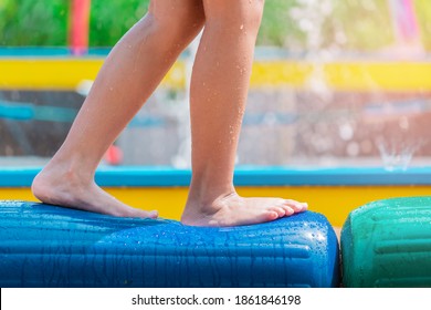 Child Foot Is Walking On Obstable Rubber Bridge In Summer Water Park.